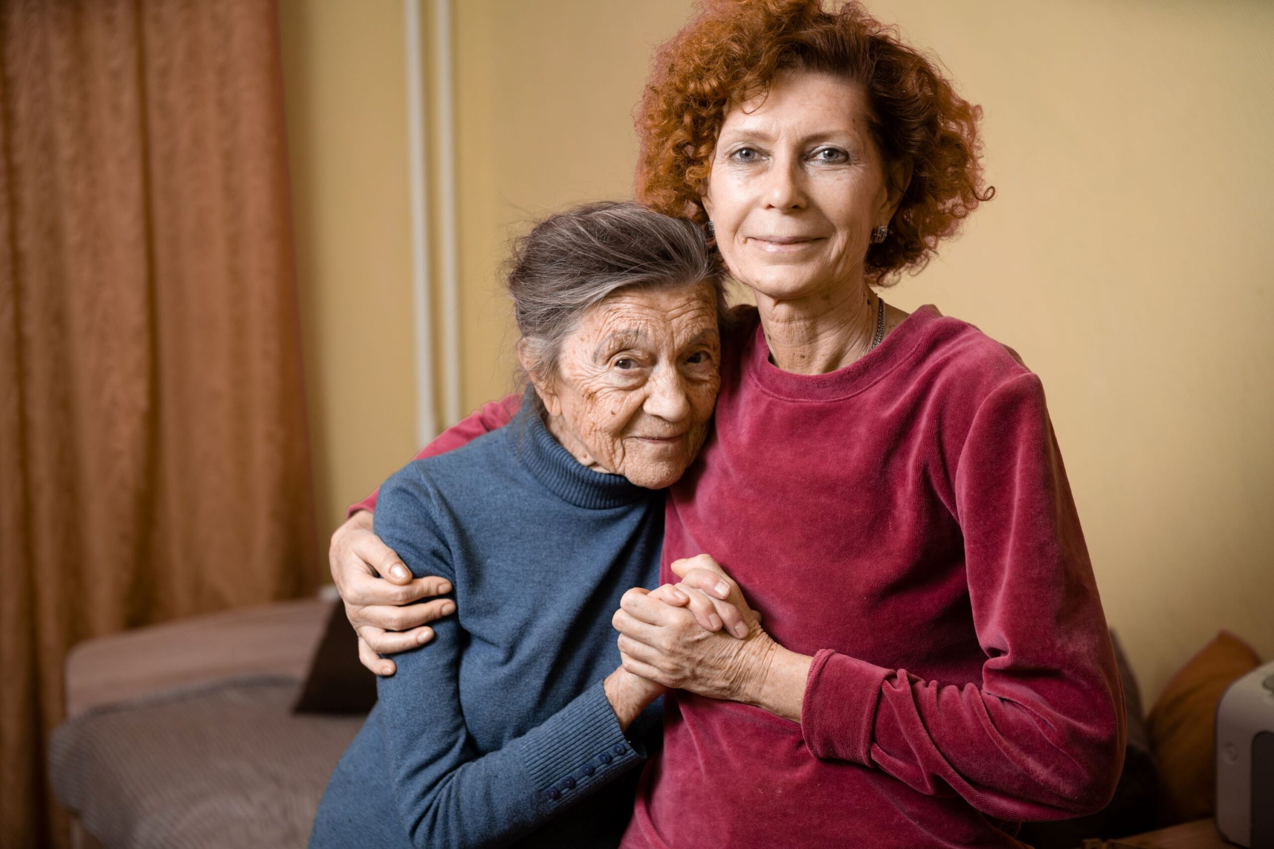 20144-elderly-woman-with-dementia-smiles-with-middle-aged-daughter-at-home-adobestock_401090987_resized